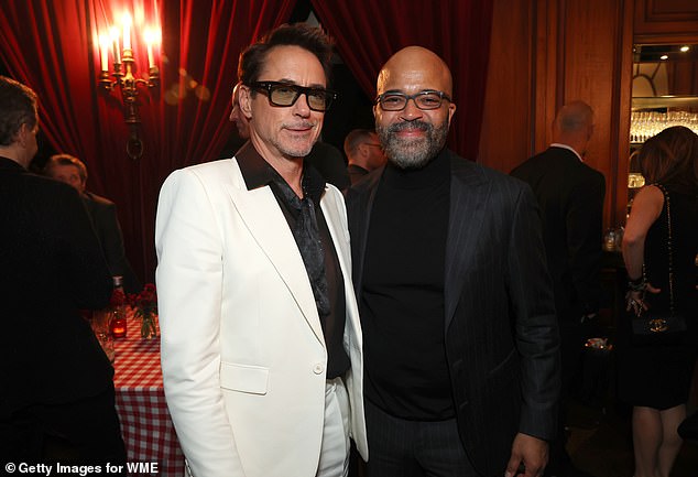 Robert Downey Jr., 58, looked like his Iron Man character Tony Stark in a white suit with a black shirt and dark glᴀsses as he posed with American Fiction actor Jeffery Wright, also 58, who wore a black suit with a black turtleneck